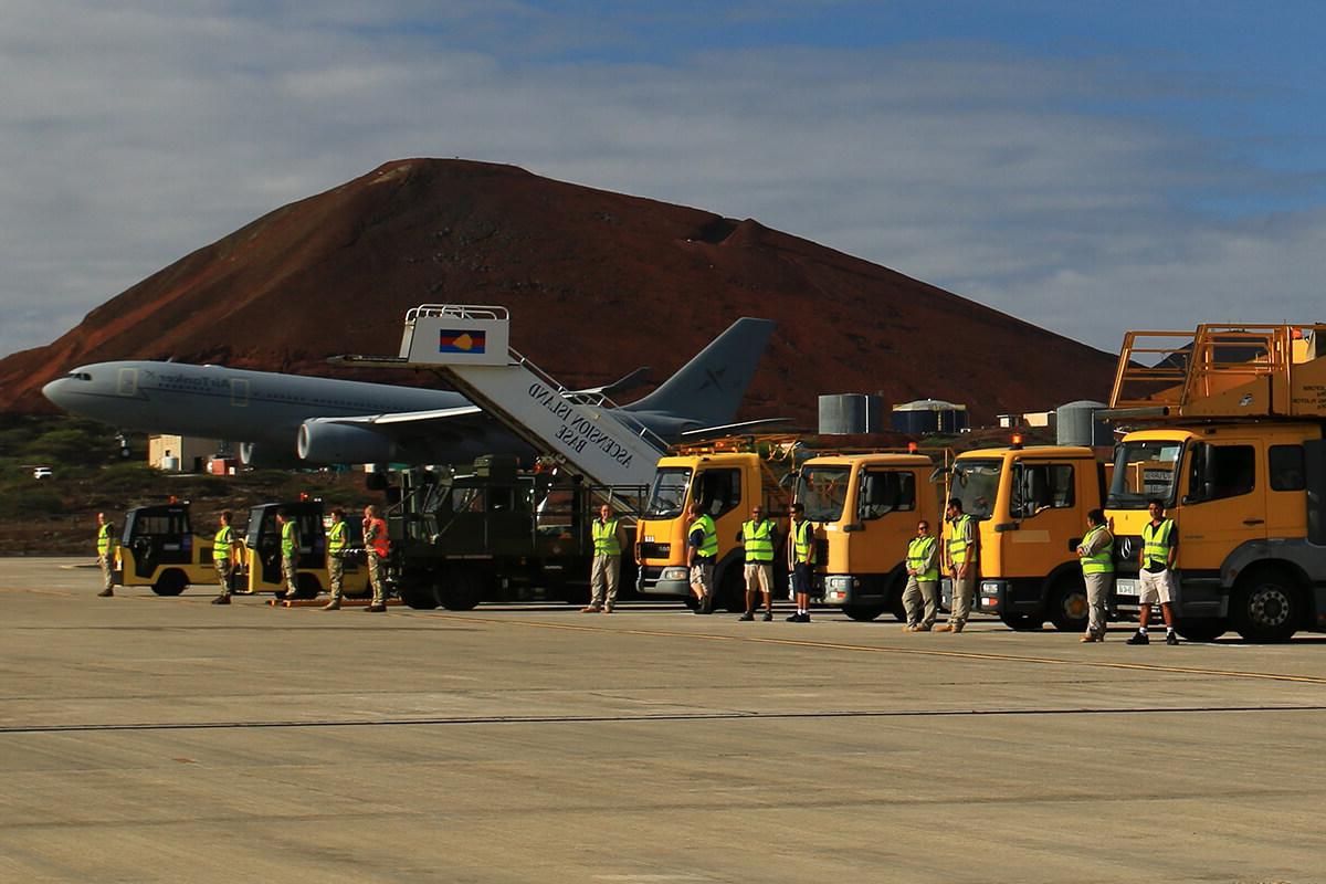 Aircraft parked on a runway with Mitie staff and other supporting vehicles nearby